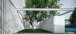 A modern landscape featuring concrete and wooden elements, including a tree and a bench.