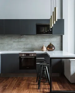 Modern black kitchen with minimalist design and white countertops.
