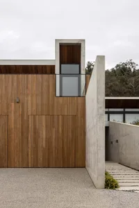 A modern house exterior featuring wood and concrete materials.