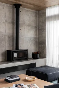 A modern industrial living room with concrete walls and a built-in fireplace.