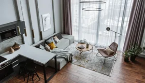 Modern living room with gray sectional sofa, wooden coffee table, and granite countertop kitchen area.