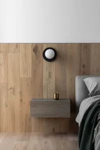 Modern minimalist bedroom with floating nightstand, wooden floor, and wall-mounted lamp.