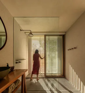 A minimalist bathroom with tiled walls, glass window, and wooden accents.