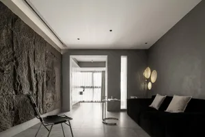 A minimalist residential interior featuring polished concrete walls, a black sofa, and modern lighting.