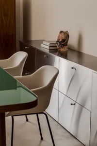 A minimalist furniture setup featuring metal cabinets and chairs, with books and a vase on top of the cabinets.