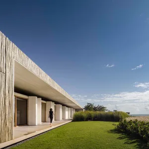 A minimalist house with wooden paneling and greenery surrounding it.