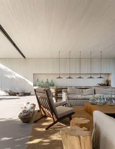 A modern minimalist living room with stone flooring, wooden furniture, and concrete walls.
