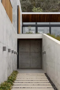 Modern entrance pathway leading to a concrete staircase, featuring minimalist design and sleek lines.