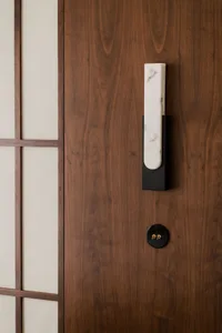 A modern entryway featuring a wooden door with a white marble handle and a black light switch.