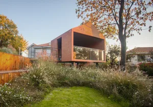 A modern house with a brick exterior, large glass windows, and a concrete base.