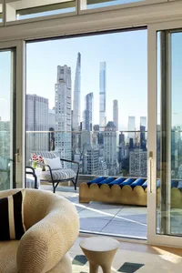 Modern interior design featuring a balcony with glass and metal details, offering a panoramic cityscape view.