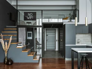 A modern interior design featuring wooden stairs, glass walls, and concrete flooring.