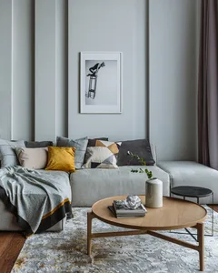 Modern living room featuring a sleek, glass-topped coffee table with decorative elements, a cozy sofa adorned with colorful c