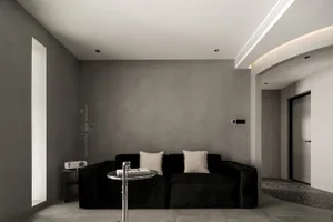 Modern minimalist living room with concrete walls and black furniture.