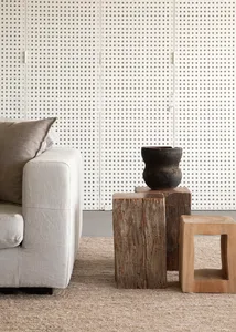 A rustic industrial living room featuring a white couch, wooden stools, and a textured rug.