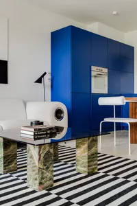 A modern apartment interior featuring minimalist decor with marble coffee table and glass cabinets.