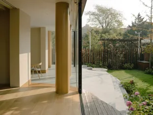 A modern residential exterior featuring wooden columns and a garden view.