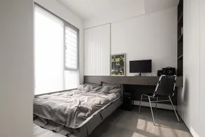 A modern bedroom with grey bedding and a minimalist design.