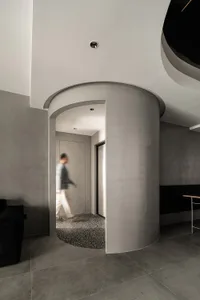 A modern entryway with a cylindrical concrete pillar and a curved ceiling.