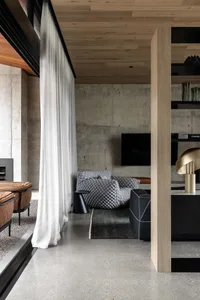 A modern industrial living room with a concrete accent wall, minimalist furniture, and sleek design elements.
