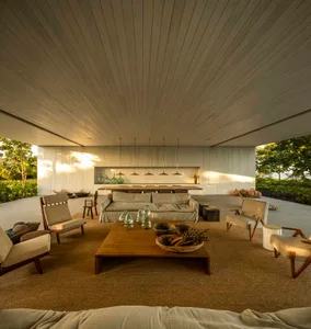 Modern living room with concrete walls and floor, featuring a low-slung sofa, wooden coffee table, and hanging pendant lights