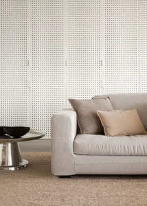 A modern living room featuring a beige fabric sofa with grey and beige cushions, a metal coffee table with a black bowl, and 