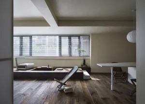 A minimalist living space featuring a wooden floor and a low wooden seating area with a small table and chairs.