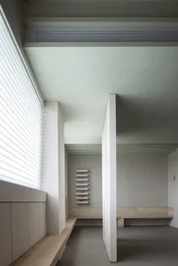 Minimalist residential interior with concrete walls, wooden benches, and metal accents.