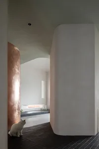 A modern living space featuring minimalist design, concrete and smooth curved walls, and elegant lighting.