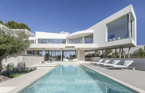 A modern residential pool house featuring glass, concrete, and stone materials.