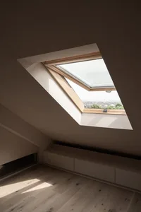 A minimalist room with a skylight, wooden floor, and white walls