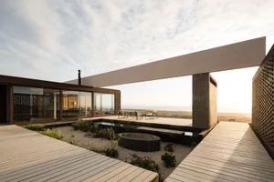 Modern house with large windows and wooden deck overlooking landscape.