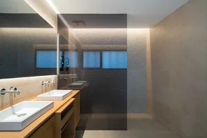 A modern bathroom with textured concrete walls and a sleek, minimalist design.