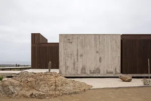 A photograph of a modern house with a minimalist exterior design featuring concrete walls and wood panels.