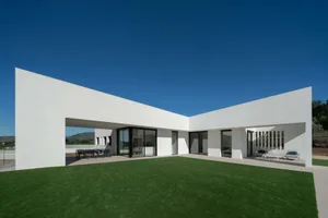 A modern concrete villa with large windows and a spacious outdoor area.