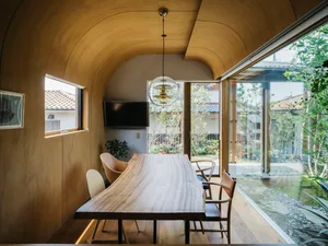 A modern dining room featuring a wooden table, chairs, and a hanging light fixture with a glass globe.