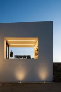 A modern house exterior with concrete walls and warm lighting during twilight.
