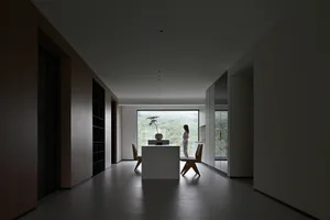 Minimalist living room with wood furniture and a large window overlooking nature.