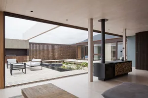 A modern living room with wooden flooring, minimalist furniture, and a fireplace.