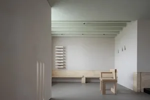 A minimalist interior with white wood furniture, shelves, and bench.