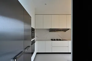 A modern minimalist kitchen with white cabinets, stainless steel appliances, and a marble backsplash.