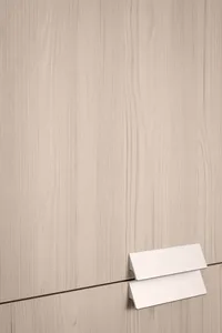 A close-up view of a modern minimalist wooden cabinet with a simple metallic handle