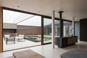 A modern extension of a residential building featuring clay and metallic materials, with a blend of indoor and outdoor living