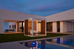 A modern residential exterior featuring a wooden and concrete patio structure with a sofa and table at dusk.