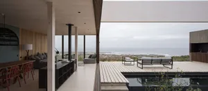 Modern vacation home terrace featuring a wood deck with furniture and ocean view.