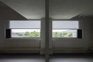 Modern architectural view with metal blinds covering large windows showcasing outdoor scenery.