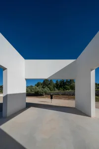 A minimalist concrete architectural space with a clear blue sky in the background.