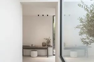 A minimalist interior space featuring glass walls, wooden furniture, and leather accents.