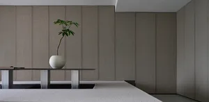 A minimalist interior with textured fabric walls and a sleek table holding a vase with a single plant.