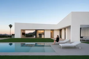Modern minimalist home exterior with white concrete exterior walls and a large swimming pool.